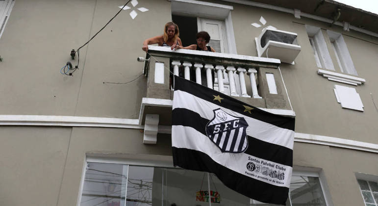 Torcedoras hasteiam a bandeira do Santos em casa próxima à Vila Belmiro