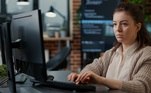 Mulher branca trabalha em frente à tela de um computador. Freepik / DCStudio