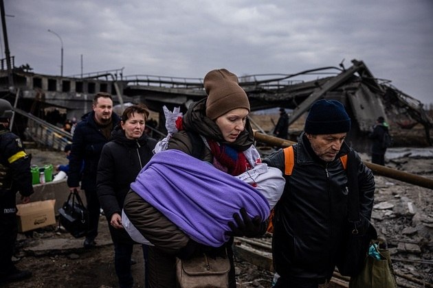 Mulher carrega beb&ecirc; enquanto cruza uma ponte destru&iacute;da ap&oacute;s bombardeio na cidade de Irpin, noroeste de Kiev