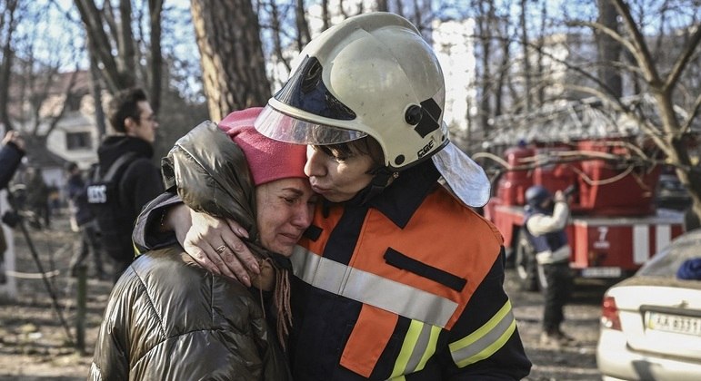 Mulher chora abraçada a socorrista após bombardeio em Kiev
