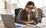 Mulher com expressão de desânimo faz as contas em frente a um computador. Freepik