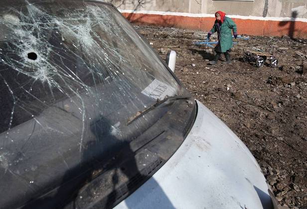 Mulher observa carro destruído após ataque russo