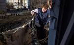 Mulher recolhe o que sobrou na varanda de seu apartamento destruído após bombardeio russo em Kiev