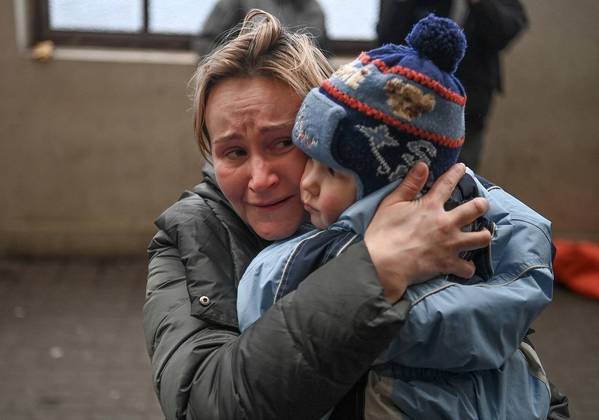 Mulher segura criança enquanto aguarda embarque em trem para se refugiar na Polônia