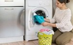 Mulher tira roupas da máquina de lavar com abertura frontal. Freepik
