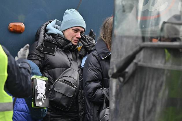 Mulher ucraniana chora ao entrar em ônibus para buscar abrigo na Polônia