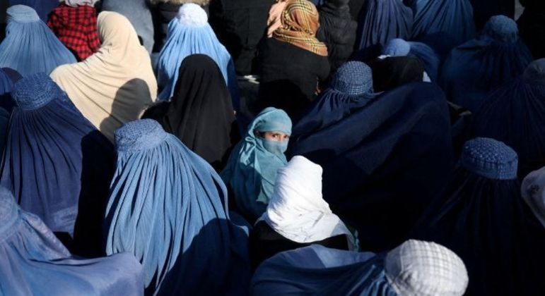 Menina sentada em meio a uma multidão de afegãs, em Cabul