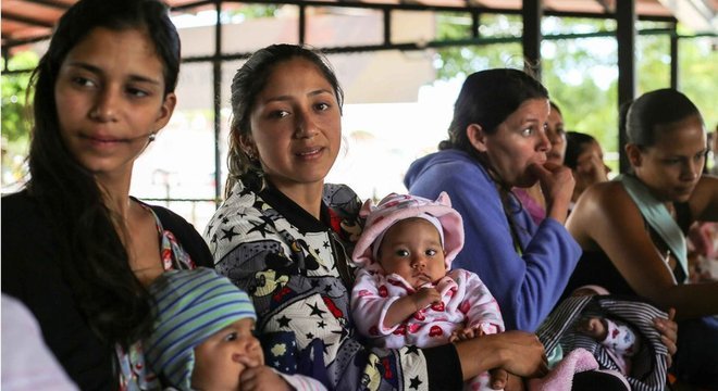 Celene Cacique (ao centro) diz que é difícil conseguir vacina na Venezuela. Do lado colombiano da fronteira, um posto de saúde oferece imunização gratuita aos bebês que chegam, mas a fila é grande