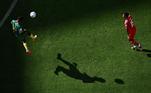Belíssima imagem com a sombra no chão e o camaronês voando com a bola pelo alto