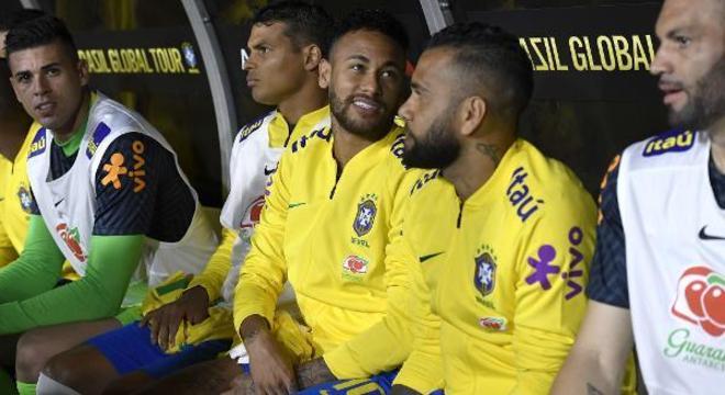 Neymar reserva, despreocupado com o jogo. Ao lado do parceiro Daniel Alves