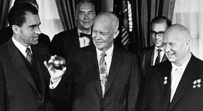 Um presente jocoso: olhado pelo premiê soviético Khrushchev (à direita) e pelo vice-presidente Richard Nixon (esquerda), Dwight Eisenhower segura uma cópia da esfera enviada à Lua a bordo da Luna 2, em 1959