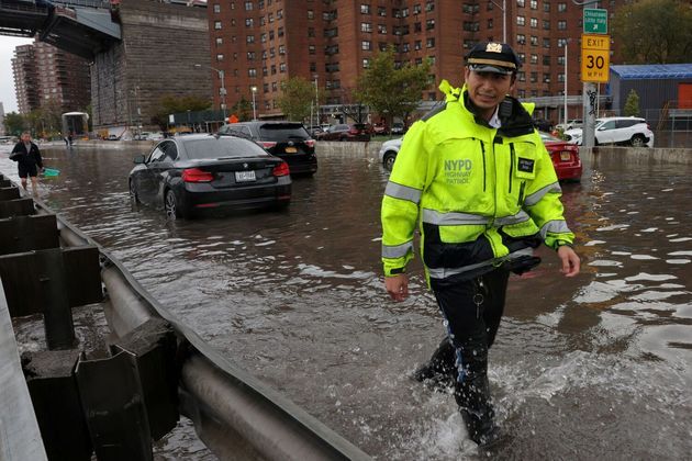 Um policial de trânsito do Departamento de Polícia de Nova York caminha em uma rua alagada pelas fortes chuvas que atingiram a cidade na madrugada desta quinta para sexta-feira (29)