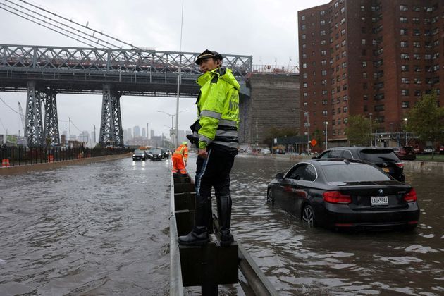 Um policial de trânsito do Departamento dePolícia de Nova York observa carros presos em uma rodovia alagada pelas fortes chuvas que atingiram a cidade na madrugada desta quinta para sexta-feira (29)