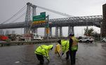 Trabalhadores do Departamento de ProteçãoAmbiental de Nova York tentam desobstruir drenos bloqueados pelas fortes chuvas que atingiram a cidade de Nova York na madrugada desta quinta para sexta-feira (29)