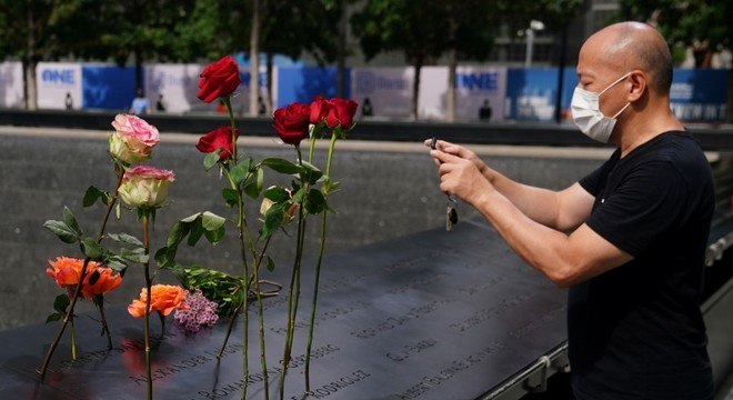 Homem fotografa flores deixadas no memorial com nomes das vítimas do 11/9
