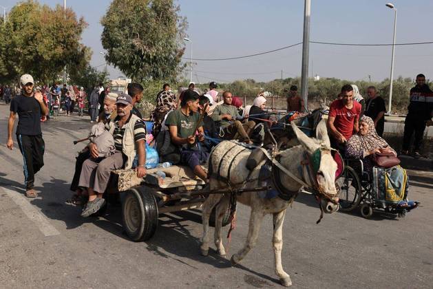 Palestinos que fogem da Cidade de Gaza em direção às áreas sul caminham e andam em carroças puxadas por burros em uma estrada em 8 de novembro de 2023, em meio aos combates em andamento entre Israel e o grupo terrorista palestino Hamas