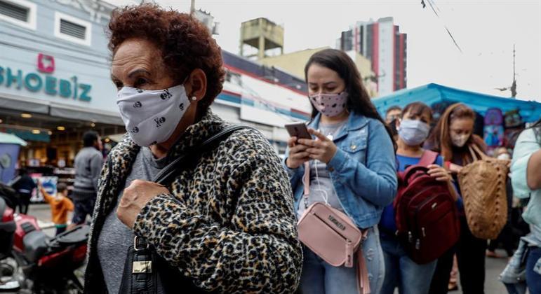 Pessoas com máscara fazem fila em comércio de São Paulo