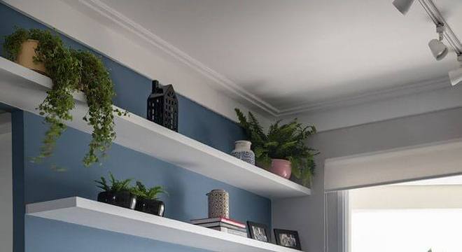 Parede azul com puff preto na decoração