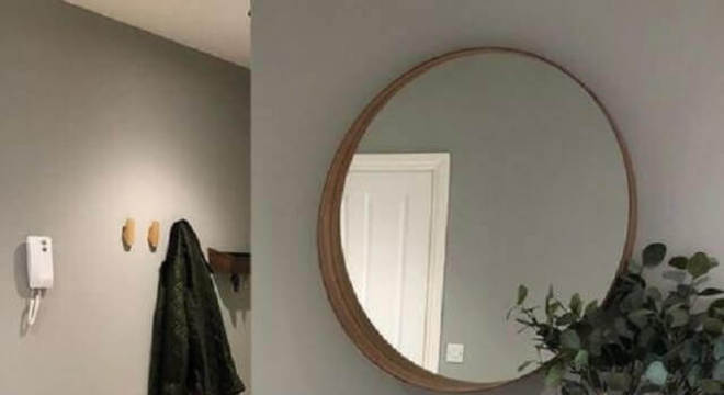 parede cinza decorada com espelho grande redondo 