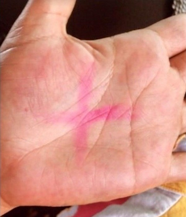 Cruz vermelha pintada na palma da mão com batom por uma mulher, como símbolo do pedido de socorro (Reprodução/Record TV)