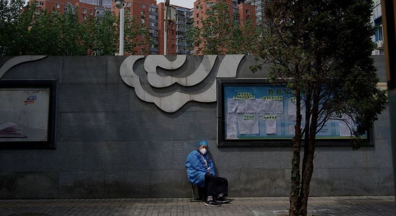 Trabalhador descansa em área externa em rua vazia de Pequim