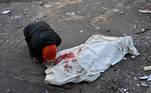 Pessoa chora diante de um corpo no meio da rua, após ataque russo a Kiev