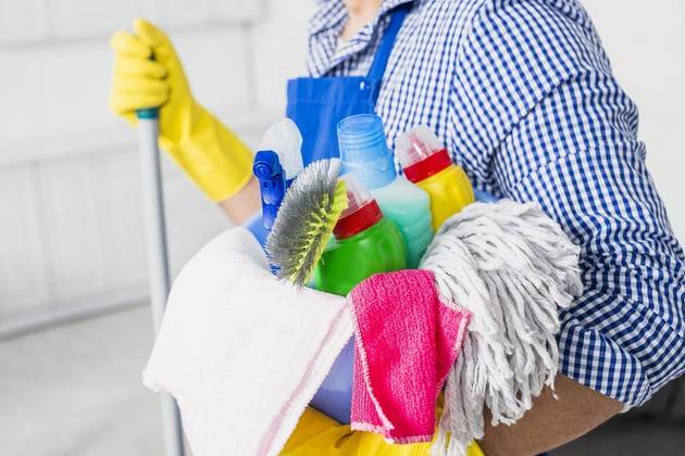Pessoa segura um kit com produtos de limpeza. Freepik