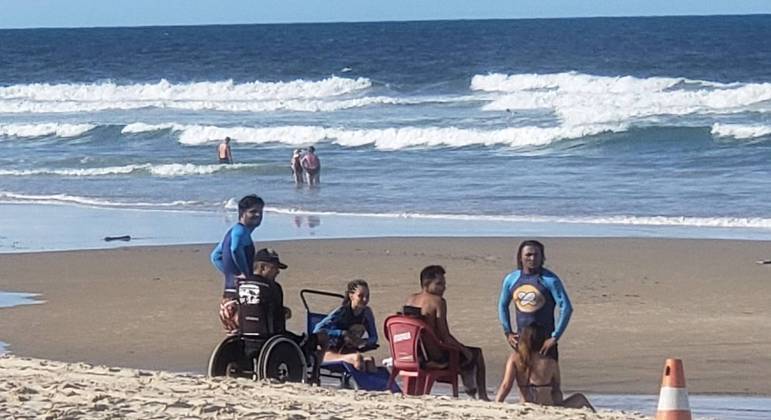 Pessoas cadeirantes curtindo a praia com o apoio de profissionais