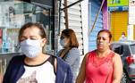 Pessoas com e sem máscara trafegam em rua comercial de São Miguel Paulista, em SP