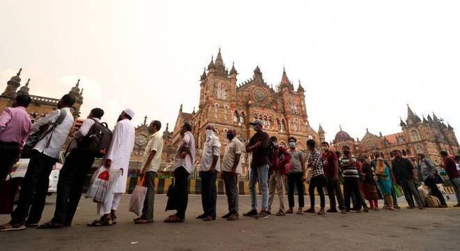 Pessoas aguardam em fila para entrar em ônibus de passageiros em Mumbai