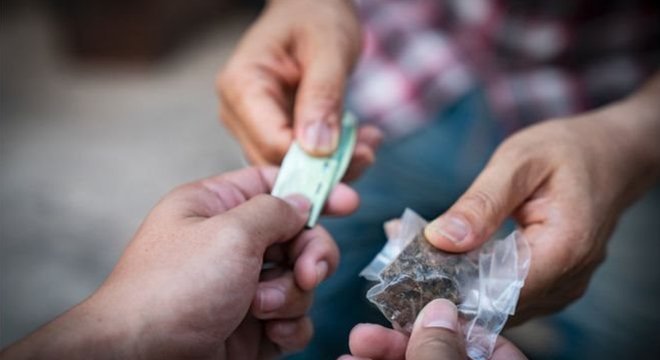 Pessoas fazem transação de compra de drogas