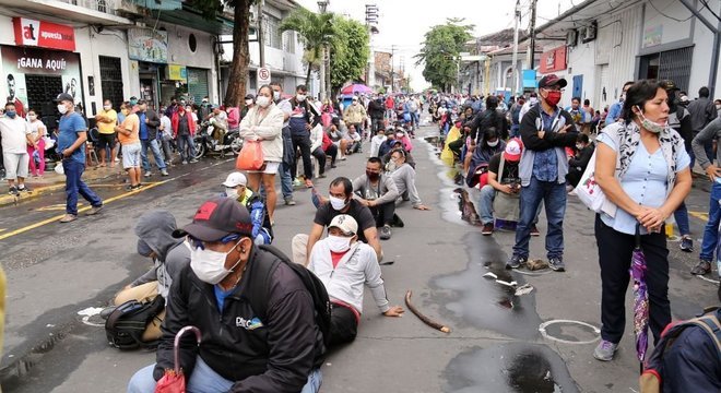 Pessoas fazem fila do lado de fora de um banco para receber auxílio do governo na cidade de Iquitos