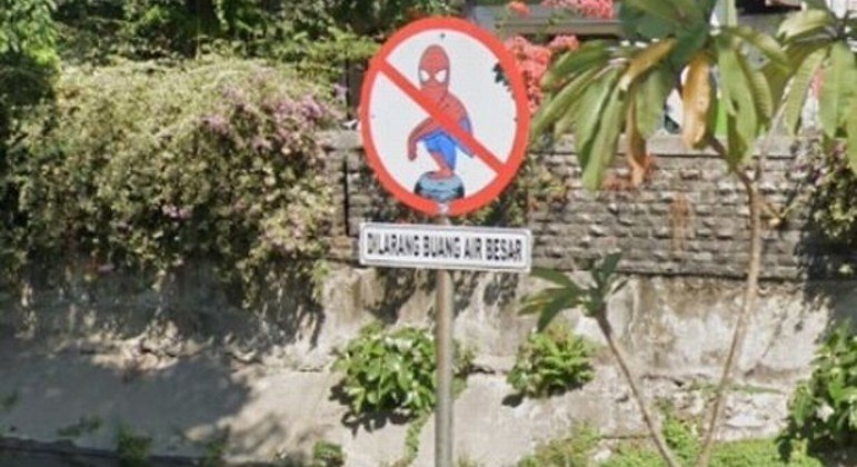 Placa à beira de canal adverte para não defecar, sob ilustração do Homem-Aranha