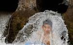 Enquanto isso, outro garoto se refrescava sob à agua, para aliviar o calor registrado em Peshawar, no Paquistão