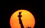 A imagem é bela e mostra a Estátua da Liberdade (em Nova York, como imaginamos que todos saibam) à frente do sol alaranjado. Mas o efeito é causado pela névoa de incêndios florestais no paísNÃO PERCA: Ciclista escorrega em curva, cai em lago e é atacado por jacaré de 2,5 m