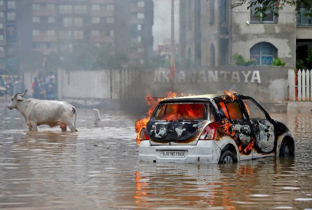 Uma semana maluca, em um mundo maluco, exige uma foto maluca! Esse estranho flagrante, com uma vaca e um carro em chamas é um exemplo. A cena foi registrada na Índia, durante as enchentes que castigaram a cidade de Ahmedabad. Segundo o Corpo de Bombeiros da região, o carro pegou fogo justamente por causa da água das chuvas, que causou um curto-circuito