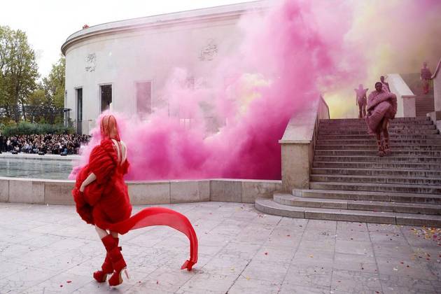 O mundo gira, e o planeta continua maluco (e calorento)! Já na Paris Fashion Week, modelos apresentam uma criação realmente esquisita, com roupas nada convencionais e fumaça rosa