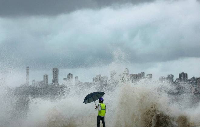 Em um momento de maré alta e agitada, um trabalhador de construção civil observa ondas que arrebentam em um canteiro