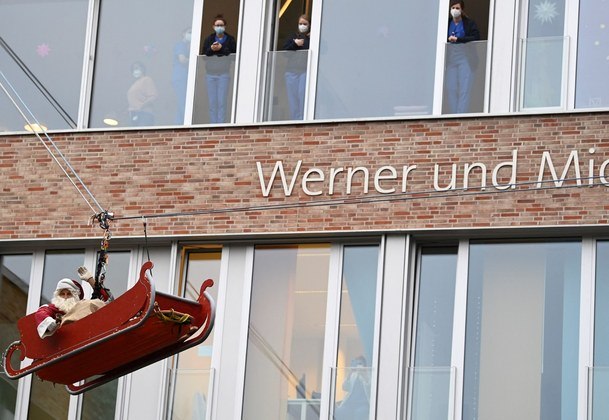 Um bombeiro vestido de Papai Noel desce do telhado em uma unidade médica infantil de um hospital do Reino Unido, para entregar presentes a crianças em Hamburgo, Alemanha. Viagem internacional do cidadão!