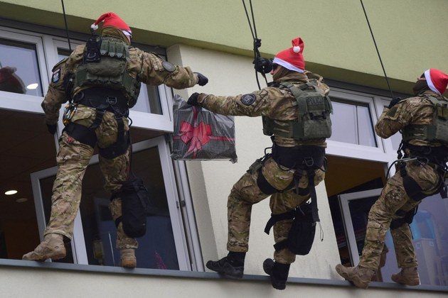 Policiais antiterroristas poloneses penduram-se do lado de fora das janelas para entregar presentes aos pacientes de um hospital infantil em Rzeszow, Polônia