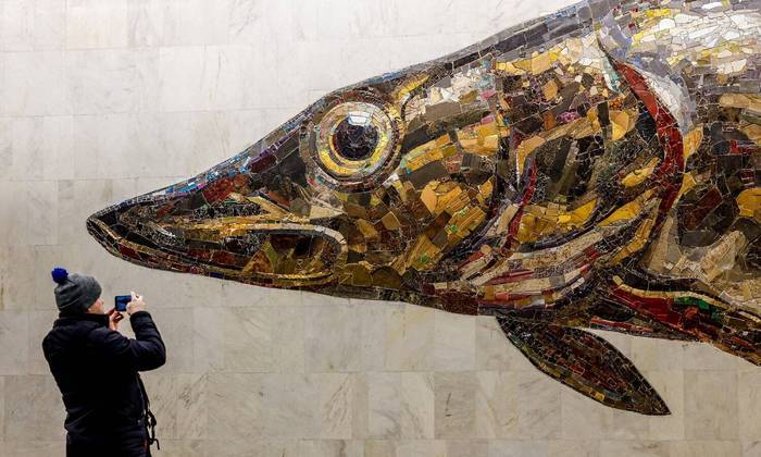 Um homem tira uma foto de uma imagem em mosaico de um peixe lúcio na estação Nagatinsky Zaton, recém-inaugurada no metrô de Moscou, na Rússia