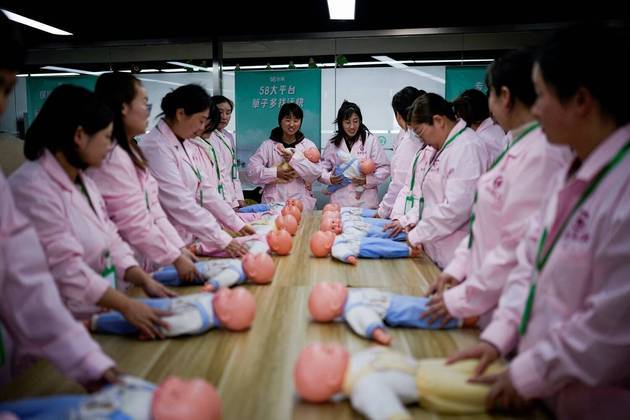 Em Xangai, na China, mulheres treinam com bonecas de plástico enquanto participam de uma aula de habilidades de enfermagem para cuidadores de confinamento