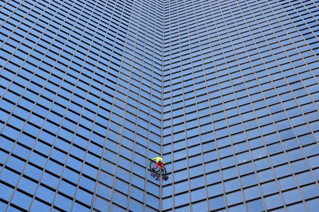 O alpinista francês Alain Robert escala o arranha-céu Tour Total Energies Coupole para pedir 