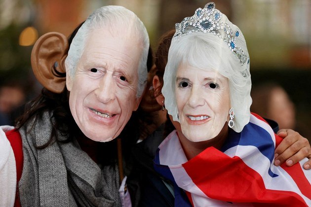 Pessoas com máscaras do rei Charles da Grã-Bretanha e da rainha Camilla esperam para assistir à cerimônia de coroação do rei Charles 3º, do Reino UnidoVALE SEU CLIQUE: Corvo pinta quadros disputados em lojas e já foi comparado a artista abstrato famoso