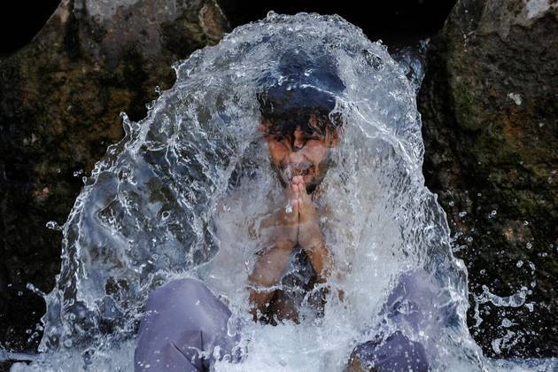 Um homem agradece enquanto se refresca em um cano de água, durante um verão muito quente e úmido em Peshawar, no PaquistãoCONTINUE POR AQUI: Investigadores amadores afirmam que pinturas de séculos atrás mostram iPhone e tênis Nike