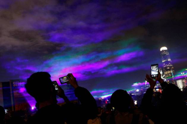 Turistas e moradores embasbacados tiram fotos de uma aurora boreal, contemplada no céu de Hong Kong, na China