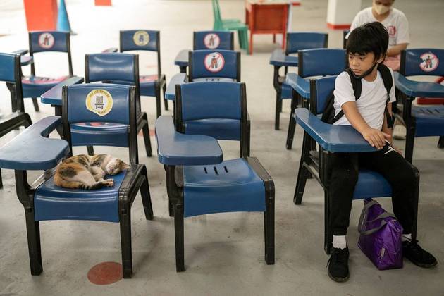 Gato também estuda, como descobriu esse jovem aluno que dá uma olhada em um felino dormindo em uma cadeira, durante o primeiro dia de aulas presenciais em uma escola pública na cidade de San Juan, Filipinas