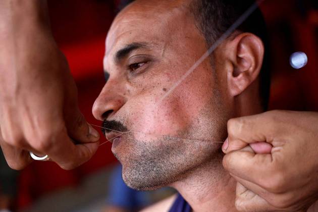 A navalha é para os fracos. Said Hussam, um barbeiro egípcio de 20 anos barbeia com linha de costura um dos 99 migrantes a bordo do barco de resgate da ONG Proactiva Open Arms UnoVALE SEU CLIQUE: Estilo retrô: conheça os jovens vencedores do campeonato de mullets dos EUA