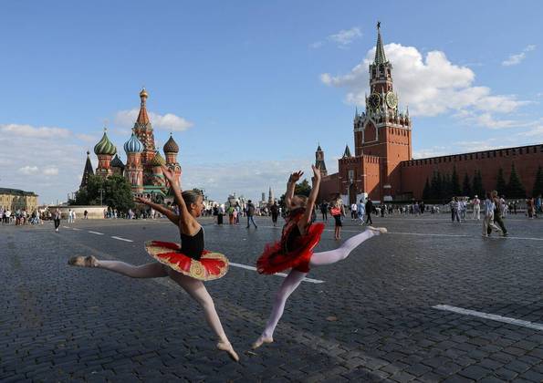 Do outro lado da fronteira, bailarinas posam na praça Vermelha, no centro de Moscou, capital da Rússia