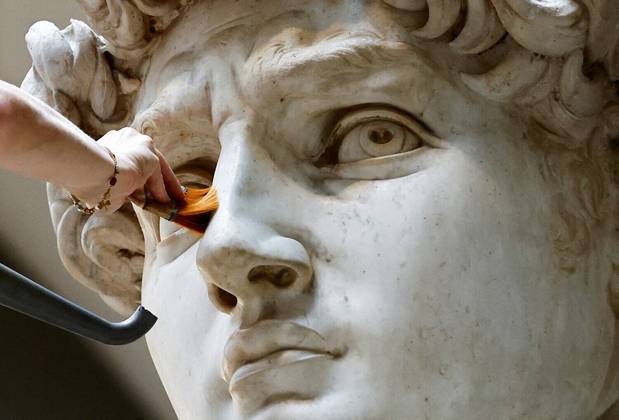 A restauradora Eleonora Pucci limpa poeira e detritos da famosa estátua de David, de Michelangelo, usando um aspirador e uma escova de fibra; na Galleria dell'Accademia, em Florença, Itália